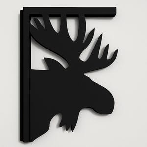 May include: Black metal wall bracket featuring a moose head silhouette. The bracket has a right-angle design with a decorative moose head cut-out. The moose head has detailed antlers and a defined profile. The bracket is designed for wall mounting and adds a rustic touch.
