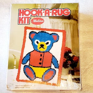 May include: A vintage "Hook-A-Rug Kit" by Malina, featuring a colorful teddy bear design. The rug kit includes a blue bear with a red vest and yellow shorts. Approximate finished size is 20" x 27".