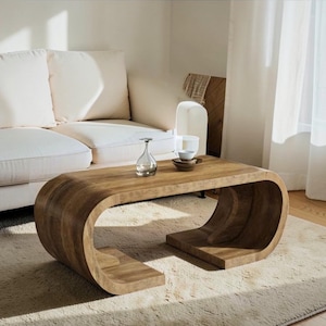 Op de afbeelding: Een witte keramische mok met een zwart handvat en de tekst "But First, Coffee" in een vetgedrukte, zwarte letter. De mok staat tegen een vage achtergrond. De mok is ongeveer 10 cm hoog.