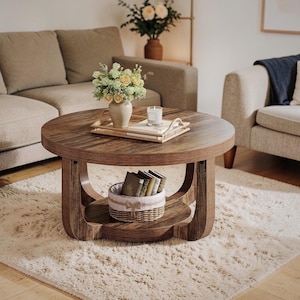 May include: A round wooden coffee table with a lower shelf and a decorative basket. The table has a dark brown finish and is topped with a tray holding a vase of flowers and a candle. The table sits on a fluffy, light-colored rug.