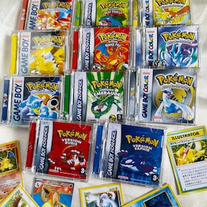 Peut inclure: Plusieurs cartouches de jeux Pokémon Game Boy et Game Boy Advance dans des boîtiers transparents, avec des titres de jeux et des illustrations de personnages. Également des cartes à collectionner Pokémon avec des illustrations et du texte japonais.