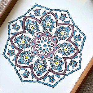 May include: A decorative tray with a white surface and a detailed floral mandala design. The mandala features blue, purple, and yellow accents, framed by a wooden border. The floral pattern is symmetrical and intricate.