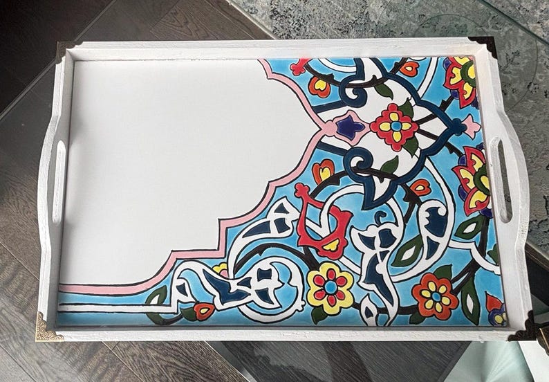 May include: White serving tray with a decorative corner featuring a blue, red, yellow, and pink floral design. The tray has white handles and gold corner accents.
