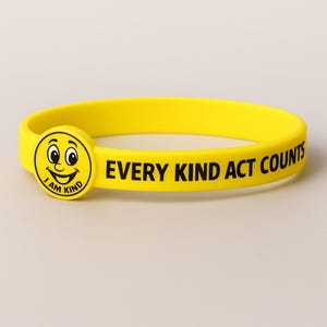 Puede incluir: Una pulsera de silicona amarilla brillante. El texto "EVERY KIND ACT COUNTS" est&aacute; impreso en negro. La pulsera presenta un emblema circular con una cara sonriente y las palabras "I AM KIND".