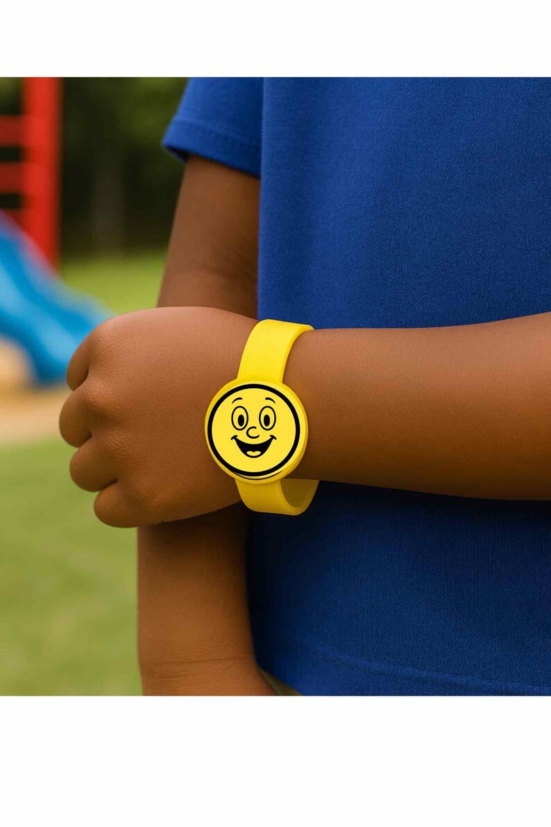 Puede incluir: Una pulsera de silicona amarilla con un dise&ntilde;o de cara sonriente. La esfera del reloj es un c&iacute;rculo con un contorno negro, con ojos, nariz y boca sonriente. La pulsera est&aacute; sujeta a una mu&ntilde;eca.