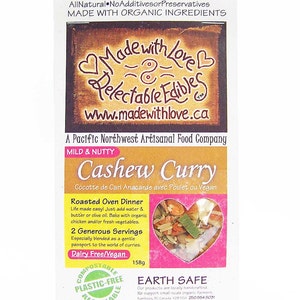 May include: A package of Cashew Curry, a mild and nutty blend of organic ingredients. The packaging is compostable, plastic-free, and recyclable. It is made by a Pacific Northwest artisanal food company called Made with Love. The package features a heart-shaped window showing the curry inside. The package also includes the text "Earth Safe" and information about the company's commitment to supporting small-scale organic farmers.