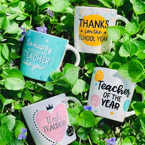 Puede incluir: Cuatro tazas de cer&aacute;mica blanca con mensajes y dise&ntilde;os tem&aacute;ticos para profesores. Una taza dice "So happy with a great TEACHER like you!". Otra dice "THANKS for the SCHOOL YEAR". La tercera dice "Best TEACHER in the world". La cuarta dice "Teacher OF THE YEAR."