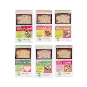 May include: Six colourful packages of frozen, ready-to-eat meals from Made with Love, a Pacific Northwest artisanal food company. The meals include Tomato Ditali, Alphabet Soup, Cashew Curry, Rosemary Focaccia, Mushroom Leek, and Shitake Mushroom. Each package features a colourful image of the meal and includes the name of the dish, a brief description, and the words "Made with Love" and "Relectable Edibles".