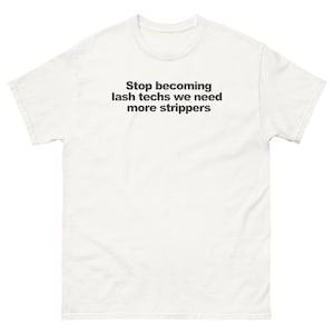 May include: A white short-sleeved t-shirt featuring black text centered on the chest that reads: Stop becoming lash techs we need more strippers. The garment has a crew neckline and a standard fit, constructed from a plain white fabric.