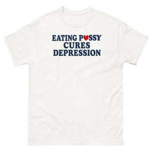 以下が含まれることがあります： 白い半袖Tシャツで、濃い青色のテキストで「EATING PUSSY CURES DEPRESSION」と書かれています。「PUSSY」という単語の「U」の文字は小さな赤いハートに置き換えられています。Tシャツはクルーネックで、標準的なフィット感です。