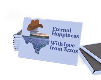 Puede incluir: Imán rectangular con fondo azul claro que presenta un sombrero de vaquero marrón y un contorno de Texas lleno de flores azules. El texto dice "Eternal Happiness With love from Texas."