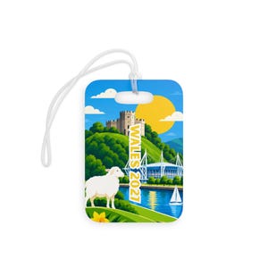 May include: A rectangular luggage tag with a white plastic loop featuring a colorful illustration of a castle on a green hill, a white sheep, a stadium, a sailboat on blue water, a yellow sun, and the vertical yellow text WALES 2021.