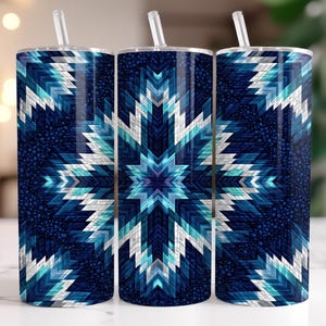 Puede incluir: Tres vasos de acero inoxidable con pajitas. Cada vaso presenta un patrón geométrico repetitivo en tonos de azul, blanco y turquesa. El diseño se asemeja a un copo de nieve o una explosión de estrellas sobre un fondo azul oscuro. Los vasos son cilíndricos.