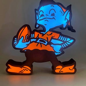 May include: A handmade wooden sign with the text "Welcome" in a playful font. The sign features a distressed white background and a dark brown frame, perfect for a front door or entryway. The sign measures approximately 12 inches wide and 6 inches tall.