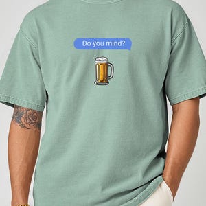 May include: A light green t-shirt with a cartoon image of a beer mug and the text "Do you mind?" in a blue speech bubble. The beer mug is filled with beer and foam.