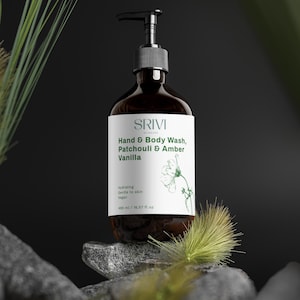 May include: A dark brown bottle of SRIVI Hand & Body Wash, Patchouli & Amber Vanilla, with a black pump dispenser. The label includes the brand name and product details. The bottle is on a stone surface with green foliage.