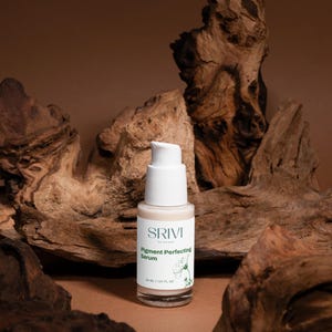 May include: A skincare serum bottle with a white pump and a label that reads "SRIVI Skincare Pigment Perfecting Serum". The bottle is set against a backdrop of textured wood and a brown background. The bottle contains 30 ml / 1.01 fl oz.
