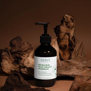 May include: A dark brown bottle of SRIVI Silk Skin Body Serum, Spices & Sandalwood. The label includes the text "Deep hydration, fast-absorbing formula, soothes and moisturizes." The bottle contains 270 ml. The background features wood.