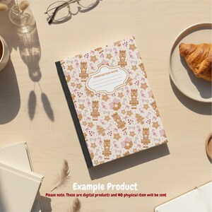 K&ouml;nnte beinhalten: Ein Notizbuch mit einem festlichen Muster aus Lebkuchen-Nussknackern, Sternen und Schleifen in Braun- und Rosat&ouml;nen. Das Cover hat einen wei&szlig;en Etikettenbereich mit den Worten "COMPOSITION BOOK". Das Buch liegt auf einer hellen Holzoberfl&auml;che.