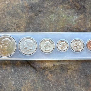Può includere: Un portamonete in plastica trasparente contenente sei monete statunitensi della serie del bicentenario 1776-1976. Il set include un dollaro, mezzo dollaro, un quarto, dieci centesimi, un nichelino e un centesimo color rame con ritratti.