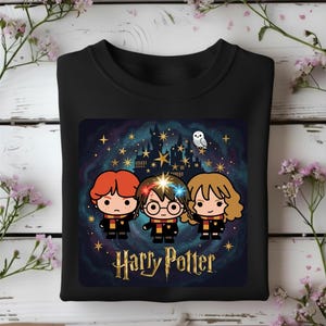 Puede incluir: Una sudadera negra de cuello redondo con un estampado gráfico de tres personajes de dibujos animados con cabello rojo, castaño y castaño claro, vistiendo uniformes escolares con bufandas. Arriba hay una silueta de castillo y estrellas.