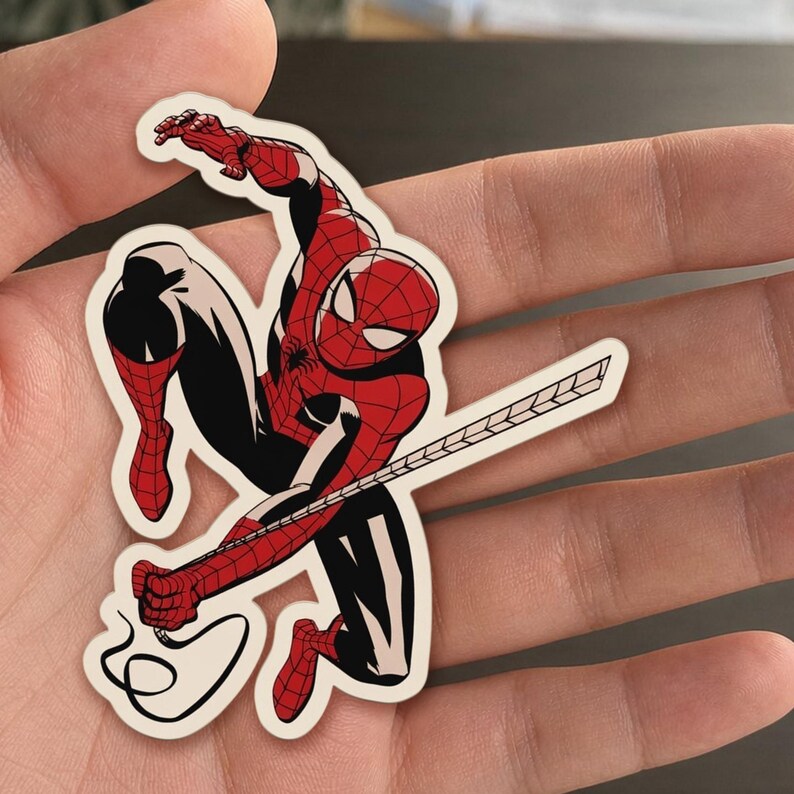 May include: A sticker featuring a dynamic illustration of Spider-Man in a classic pose. The character is depicted in his iconic red and black suit, with a web extending from his hand. The sticker has a white border.