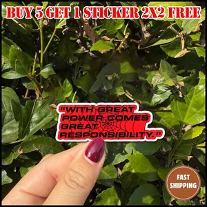 May include: A red sticker with the quote "WITH GREAT POWER COMES GREAT RESPONSIBILITY" in white text, with a spiderweb design. The sticker is held in front of green foliage. The text "BUY 5 GET 1 STICKER 2X2 FREE" is at the top.