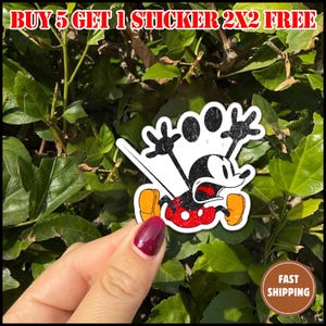 May include: A sticker featuring Mickey Mouse in a distressed, running pose with a surprised expression. The sticker has a white border and is set against a backdrop of green leaves. Text at the top reads "BUY 5 GET 1 STICKER 2X2 FREE".