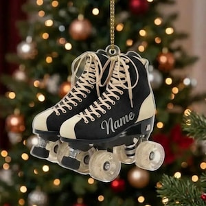 May include: A hanging ornament shaped like a pair of black and cream roller skates with beige laces. The side of the skate features the word Name in a cursive script font. The skates have clear wheels and are suspended by a gold string.
