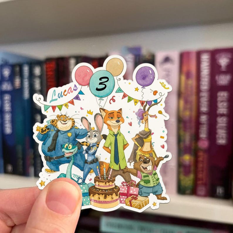 May include: A die-cut sticker featuring Zootopia characters including a cheetah, rabbit, fox, gazelle, and beaver. The design includes a birthday cake with candles, colourful balloons, confetti, and the text Lucas and 3 in a festive celebration.