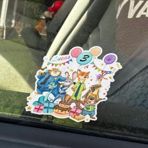 May include: A Zootopia-themed sticker featuring characters Judy Hopps, Nick Wilde, Chief Bogo, Flash, and others. The design includes a birthday cake, colourful balloons, and bunting with the text Lucas and the number 3 printed at the top.