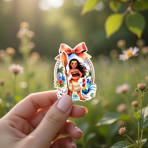 May include: A colorful sticker featuring a cartoon character with long black hair, holding a wooden oar. The sticker includes a pig, a rooster, and tropical flowers. A large red bow is at the top of the sticker.