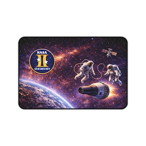 Puede incluir: Alfombrilla de ratón rectangular con diseño espacial. La imagen incluye astronautas, una nave espacial y un satélite sobre un fondo de estrellas y planetas. El logotipo de la NASA Gemini se muestra de forma destacada.
