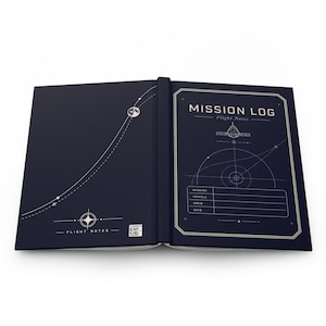 May include: An open dark blue notebook titled MISSION LOG Flight Notes. The left cover features a white orbital path and moon graphic. The right page displays a technical space diagram with fields for mission, vehicle, crew, and date information.