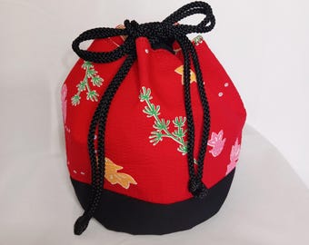 May include: A red drawstring pouch featuring a black base and black braided cord ties. The red fabric is decorated with a repeating pattern of green pine-like sprigs and small pink and yellow goldfish shapes. The text A302ZT is visible.