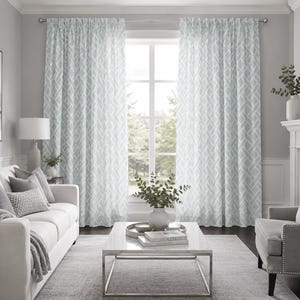 Puede incluir: Un par de cortinas de piso a techo con un patrón geométrico de celosía repetitivo en azul claro y blanco. Las cortinas cuelgan de una barra plateada sobre una ventana grande, mostrando una textura de tela semitransparente con pliegues.