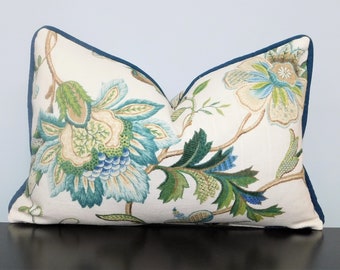 Peut inclure: Un oreiller blanc avec un motif floral dans les tons de vert, bleu et jaune. L'oreiller a une bordure bleu foncé.