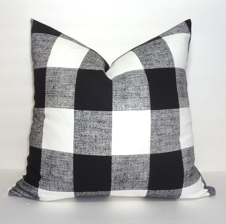 May include: Black and white buffalo check throw pillow. The pillow is made of a soft, textured fabric.
