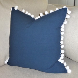 Funda de almohada azul marino lisa con pompones blancos de HomeLiving. Elige el tamaño.