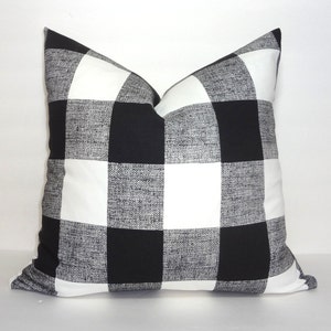 May include: Black and white buffalo check cushion. The cushion is made of a soft, textured fabric.
