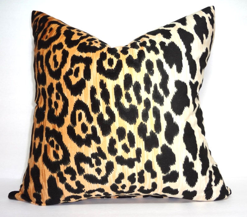 Pu&ograve; includere: Un cuscino decorativo con un motivo leopardato nero, arancione e bianco.