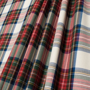 May include: Red, green, blue and white plaid fabric with a woven texture. The fabric is folded and draped, showing the pattern.