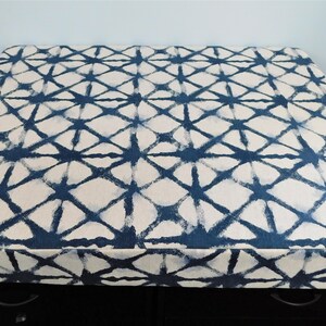 May include: A blue and white patterned fabric storage box with a geometric design. The box is made of a soft, durable fabric and has a sturdy base.