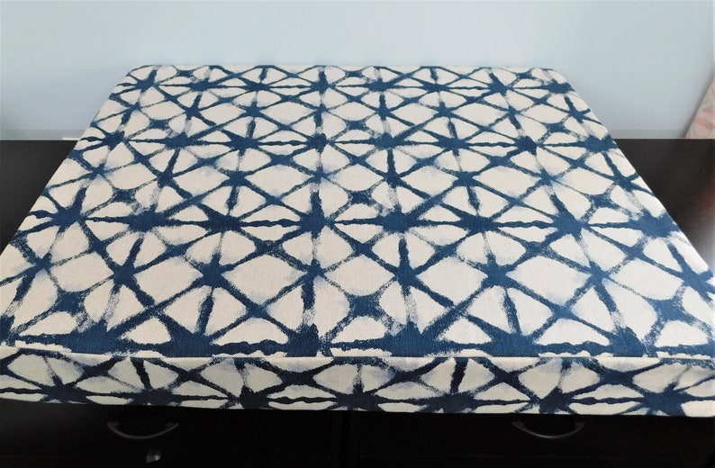 May include: A blue and white patterned fabric storage box with a geometric design. The box is made of a soft, durable fabric and has a sturdy base.