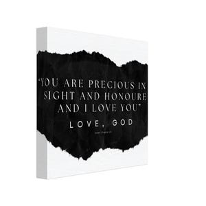 May include: A canvas print featuring a white backdrop and a prominent black, textured form. The text "YOU ARE PRECIOUS IN SIGHT AND HONOURE AND I LOVE YOU" is printed in black, along with "LOVE, GOD" and "Isaiah, Chapter 43".