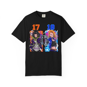 May include: Black t-shirt featuring a colorful graphic of two anime characters, labeled "17" and "18". The characters are depicted with detailed artwork and vibrant colors, set against a dynamic background. The shirt is made of a soft material.