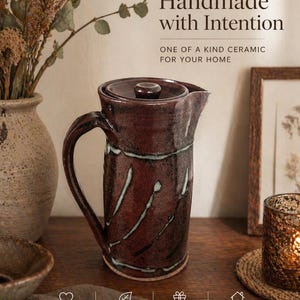 May include: A dark red ceramic pitcher with a lid and handle, with white streaks. The image includes the text "Handmade with Intention" and "One of a kind ceramic for your home."
