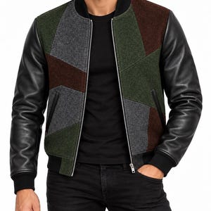 May include: A bomber jacket featuring black leather sleeves and a front panel constructed from geometric wool-blend patches in shades of charcoal gray, olive green, and dark brown. The jacket includes a black ribbed collar, cuffs, and a silver zipper.