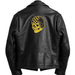 May include: Black leather jacket with a yellow and black skull and helmet patch on the back. The jacket has a classic biker style with a notched collar, zipper details, and a tailored fit. The patch features a checkered helmet design.