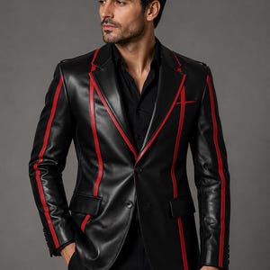 Op de afbeelding: Een zwarte leren blazer met opvallende verticale rode strepen op de voorpanden en mouwen. Het jasje heeft een reverskraag, twee knopen aan de voorzijde en twee klepzakken. Het wordt gedragen over een effen zwart overhemd met knopen.